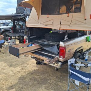Bed setup with hidden storage drawer pulled out beneath spare tire.