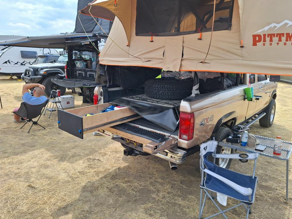 Bed setup with hidden storage drawer pulled out beneath spare tire.