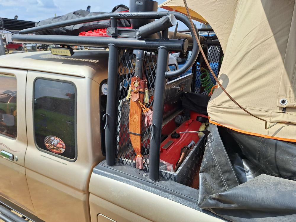 Detail of roof rack setup with LED light bar, traction boards, and PVC water tank.