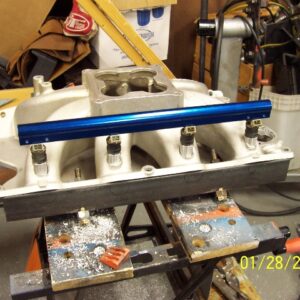 The bungs are checked with a straight edge to make sure they are all level with one another. 4 old injectors are fitted in the fuel rail and inserted without an o-ring into the bungs to stabilize them while the epoxy dries.